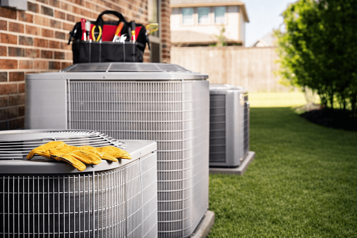 Multiple outdoor AC condensing units with technician tools ready for replacement